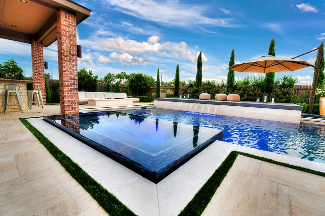 Modern backyard pool with vanishing edge, raised spa, and sleek design elements