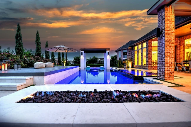 Luxury custom-built pool with sleek modern design, elevated sunbathing deck, and fire feature