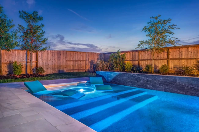 Elegant backyard pool design with travertine decking and LED lighting