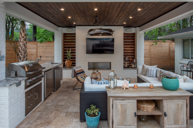 Resort-style outdoor living space featuring a covered patio, outdoor kitchen, and cozy seating area.